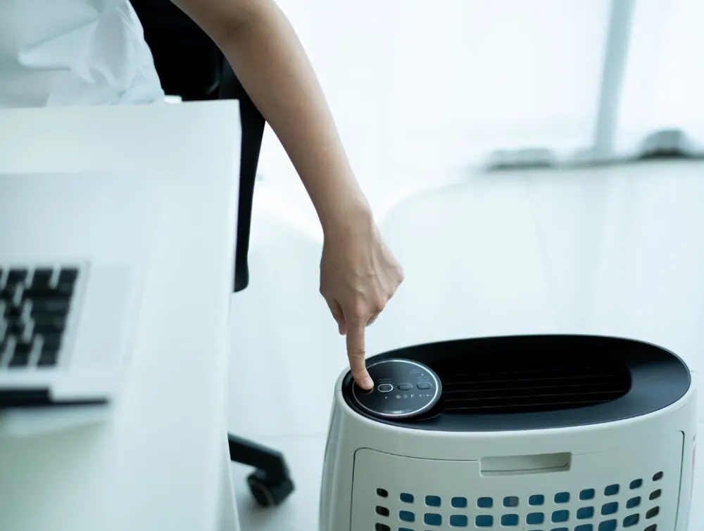 Người dùng đang bật máy lọc không khí bằng cách nhấn nút nguồn, đảm bảo khởi động thiết bị một cách đúng cách