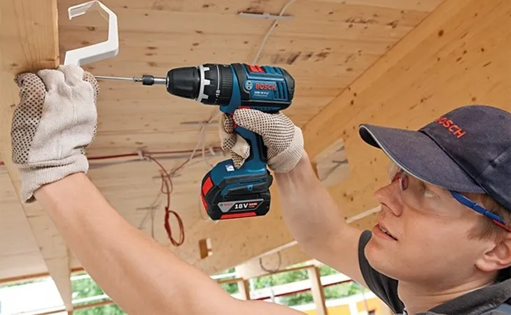 Người thợ đang thực hiện thao tác khoan trên vật liệu với máy khoan cầm tay