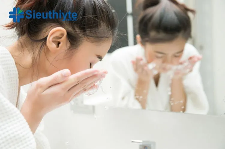 Người phụ nữ làm sạch da mặt với sữa rửa mặt trước khi sử dụng máy xông mini