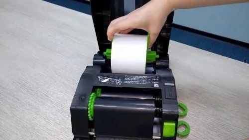 Hình ảnh minh họa chi tiết cách lắp giấy vào máy in mã vạch, đặc biệt là luồn giấy qua khe dẫn hướng và đầu in