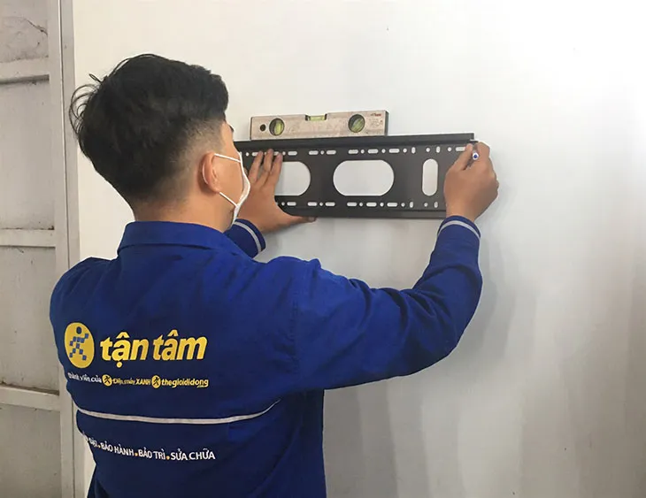 Thợ đang đo đạc và khoan lỗ để lắp đặt giá treo dàn lạnh, một bước quan trọng trong cách lắp đặt máy điều hòa
