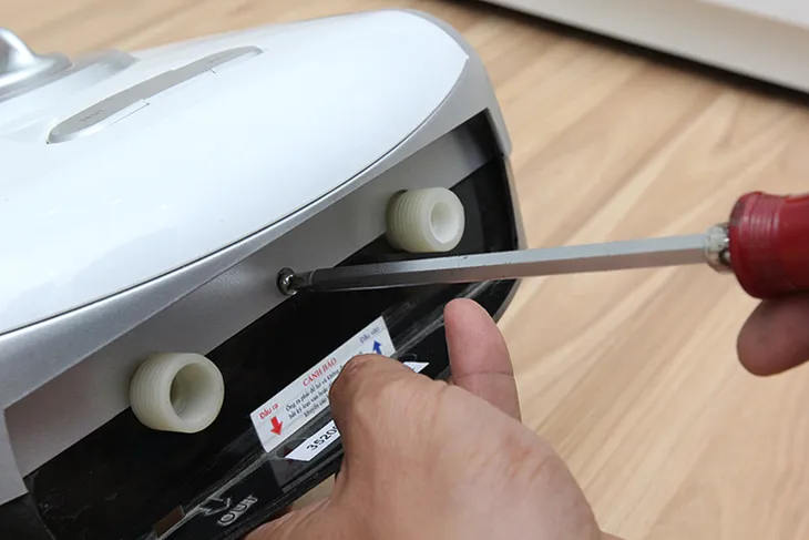 Thao tác tháo mặt nạ máy nước nóng bằng tua vít, bước đầu tiên trong việc lắp đặt