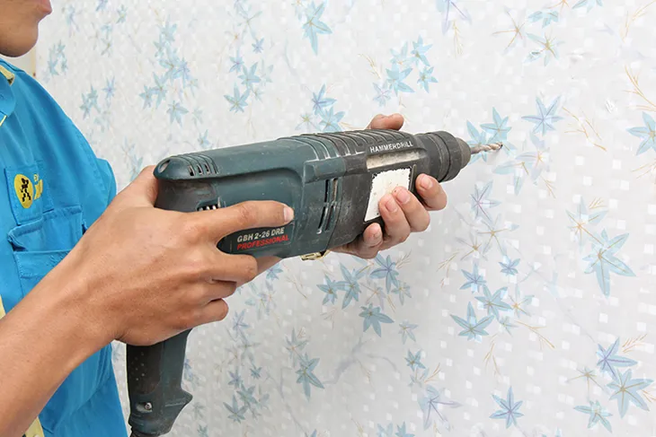 Gắn chặt máy nước nóng lên tường bằng vít sau khi đã khoan lỗ và đóng tắc kê