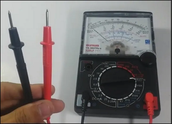 Hình ảnh một chiếc máy đo volt kim (analog) với các que đo