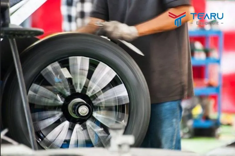 Kỹ thuật viên đang đưa bánh xe vào máy cân bằng lốp để chuẩn bị cho quy trình kiểm tra và điều chỉnh