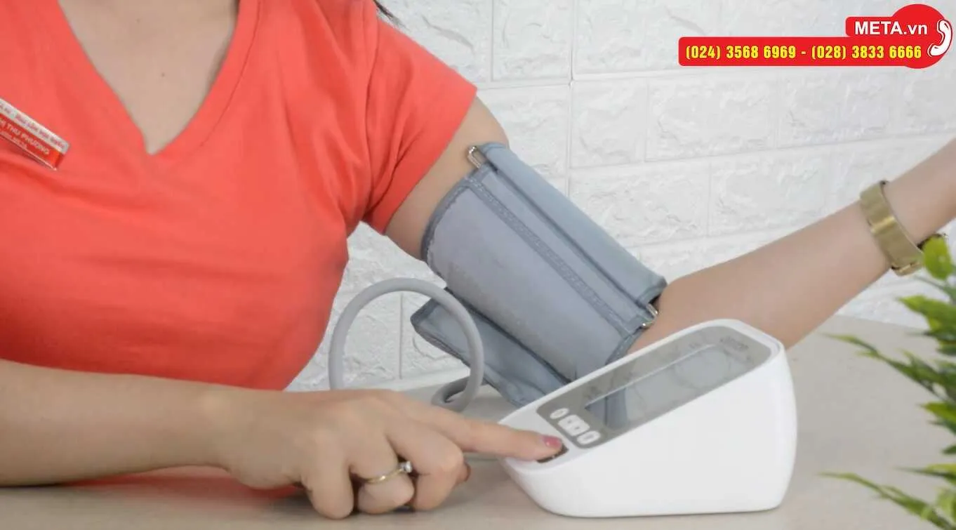 Thực hiện đo huyết áp bằng máy Omron JPN600, hiển thị màn hình và vòng bít đang hoạt động