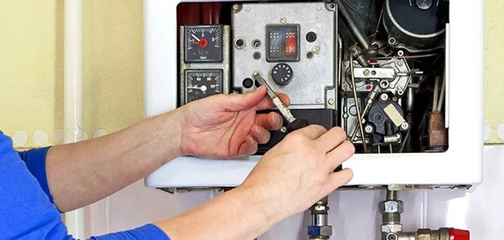 Kỹ thuật viên đang bảo dưỡng máy nước nóng gián tiếp Ariston, thể hiện tầm quan trọng của việc vệ sinh định kỳ để duy trì hiệu suất và an toàn