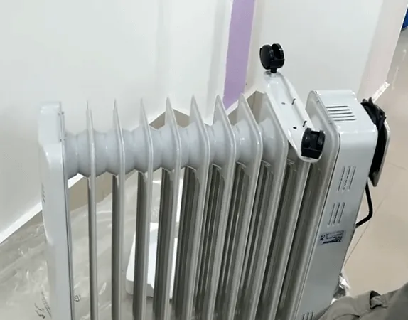 Người dùng đặt chân của máy sưởi Tiross vào giữa hai thanh nhiệt để cố định chắc chắn