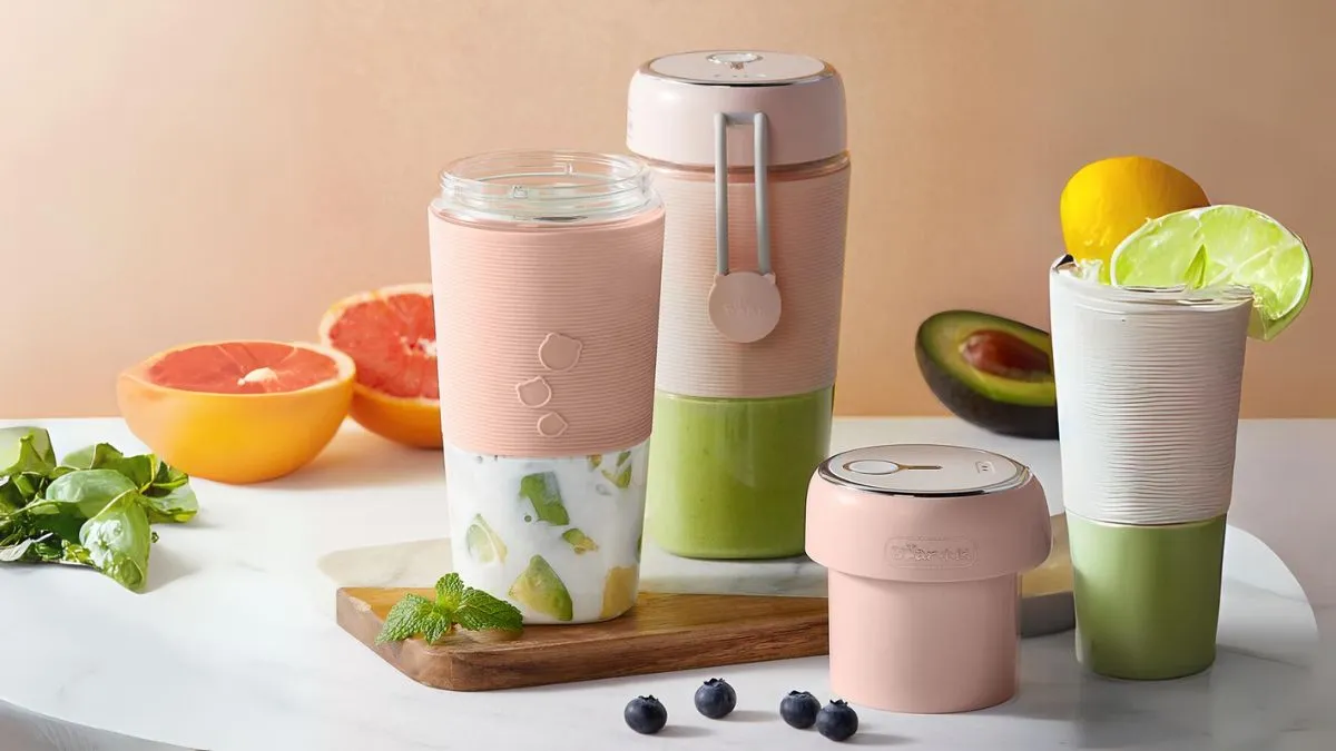 Một người phụ nữ đang sử dụng máy xay sinh tố cầm tay mini để pha chế đồ uống dinh dưỡng, minh họa sự tiện lợi khi sử dụng.