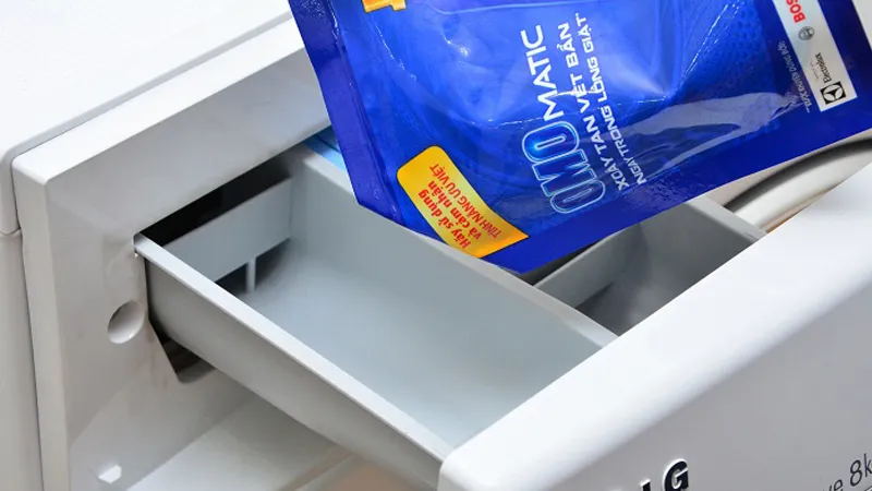 Chai nước giặt đậm đặc được đặt cạnh quần áo trong lồng giặt, gợi ý phương pháp cách sử dụng nước giặt cho máy giặt khi không có ngăn chuyên dụng