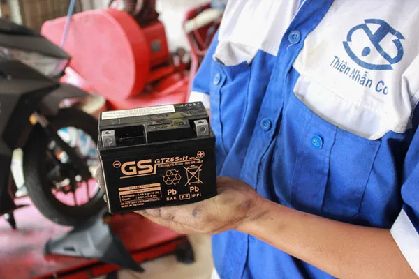 Người lớn đang kiểm tra động cơ của xe máy điện trẻ em để xử lý sự cố