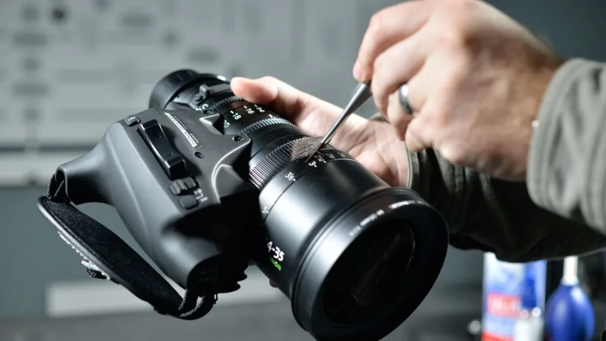 Người dùng đang thực hiện lưu ý quan trọng trước khi tháo lens máy ảnh để đảm bảo an toàn thiết bị