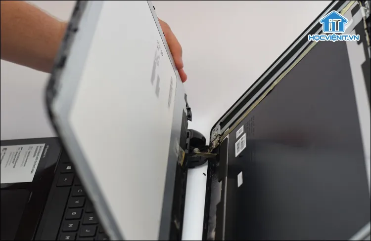 Đặt màn hình úp xuống bàn phím laptop HP sau khi tháo khung viền