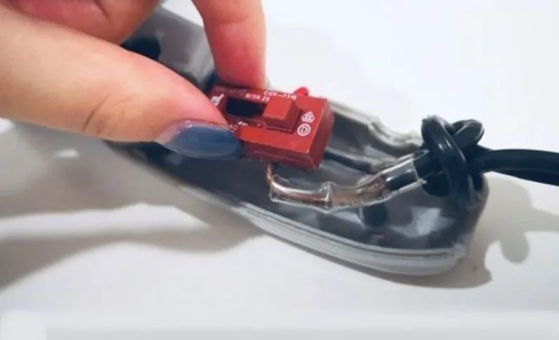 Các công tắc điều khiển trên tay cầm máy sấy tóc đã được tháo rời, một phần của quy trình tháo máy sấy và cách tháo máy sấy tóc.