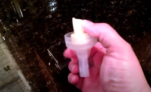 Thao tác ấn ngón tay cái để tháo van vàng của máy Medela Swing/Pump Instyle/Harmony