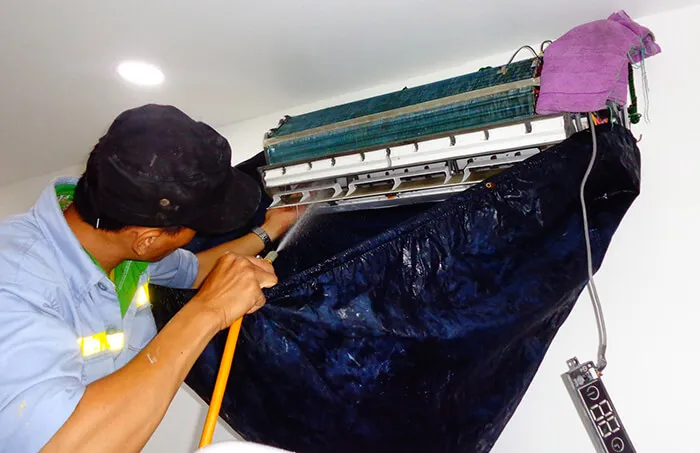 Sử dụng bình xịt chuyên dụng để làm sạch dàn lạnh, một bước quan trọng trong cách tháo vệ sinh máy lạnh Daikin.