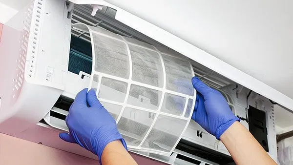 Người dùng nhẹ nhàng tháo tấm lưới lọc không khí khỏi dàn lạnh máy lạnh Toshiba để chuẩn bị vệ sinh