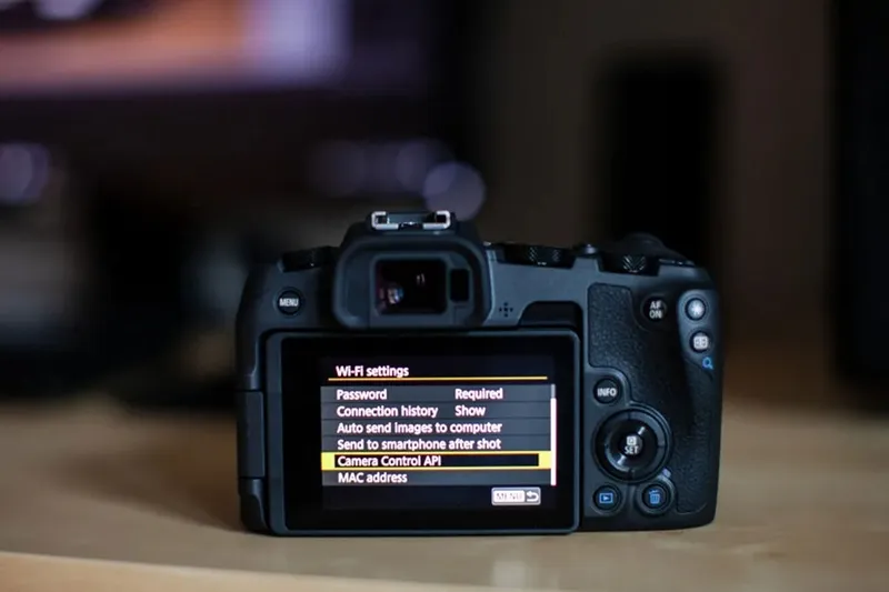 Bàn tay nhiếp ảnh gia đang điều chỉnh các thông số trên thân máy ảnh Canon, minh họa cách sử dụng máy chụp ảnh Canon để tối ưu hóa chất lượng hình ảnh.