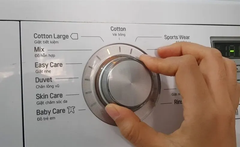 Người dùng đang nhấn nút nguồn trên bảng điều khiển máy giặt LG cửa ngang