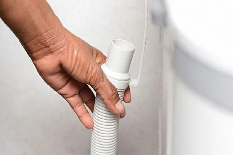 Hình ảnh minh họa cách tháo ống xả nước máy giặt Electrolux với xô hứng, đảm bảo nước thừa và cặn bẩn không tràn ra sàn.