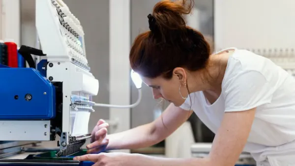 Vải được đặt dưới chân vịt của máy may Brother, minh họa giai đoạn chuẩn bị cho việc thực hiện cách sử dụng máy may brother để may vá