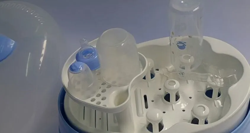 Đặt bình sữa úp ngược vào máy tiệt trùng, cùng với các phụ kiện như núm ti và nắp bình, đảm bảo chúng không bị chồng chéo để tối ưu hóa quá trình tiệt trùng