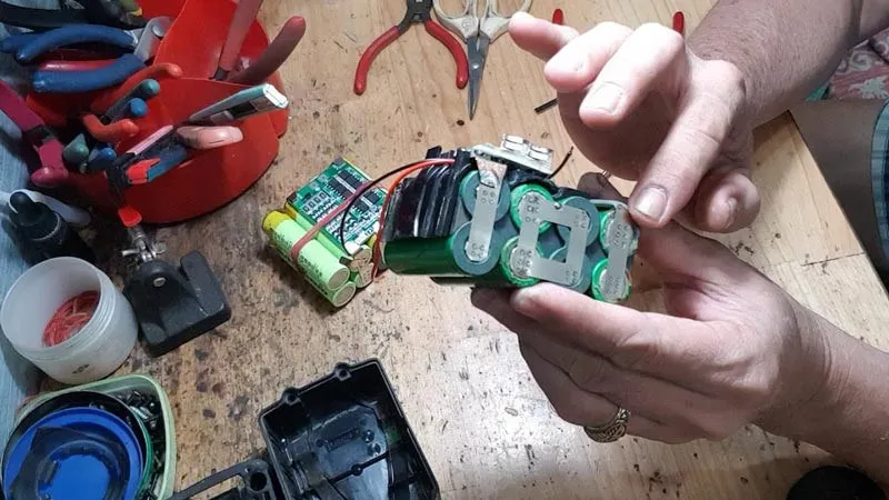 Hình ảnh một người đang kiểm tra các cell pin máy khoan