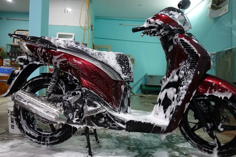 Người đang rửa xe máy một cách cẩn thận để bảo quản xe máy khi không sử dụng