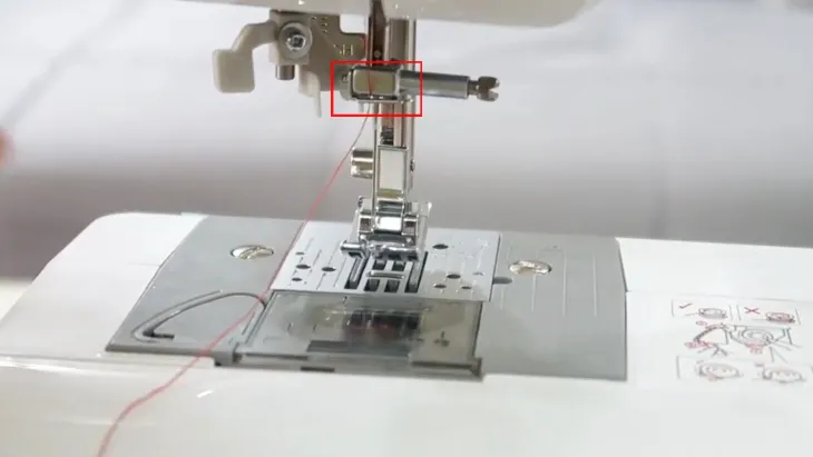 Luồn sợi chỉ qua vòng kim loại cố định chỉ ở giữa kim của máy may mini