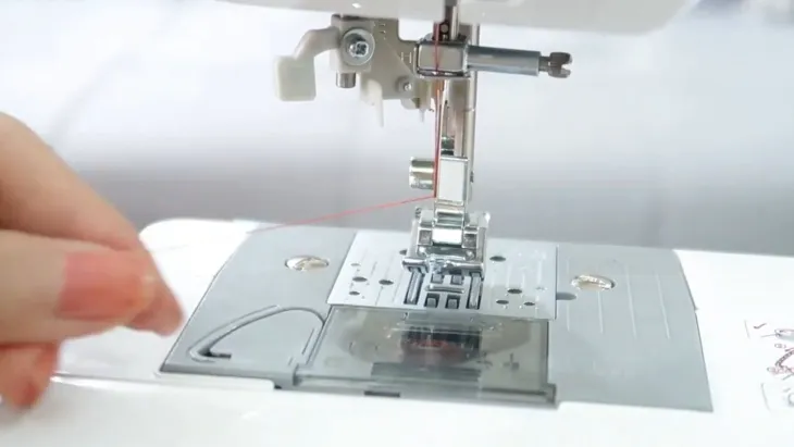 Thao tác xỏ sợi chỉ vào lỗ kim của máy may mini theo đúng chiều từ trước ra sau