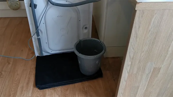 Đặt xô và khăn dưới ống để hứng nước còn sót lại khi tháo