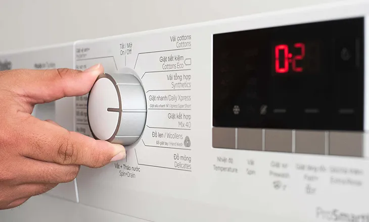 Người dùng đang xoay núm điều chỉnh trên bảng điều khiển để chọn chương trình giặt mong muốn cho máy giặt Beko 8kg