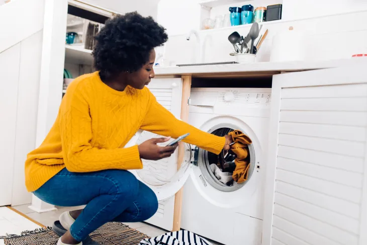 Mở cửa máy giặt và cho quần áo vào lồng giặt