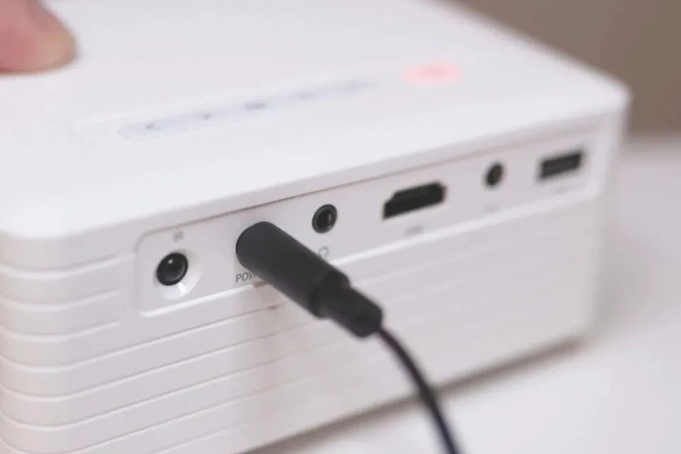 Người dùng đặt máy chiếu mini trên bàn