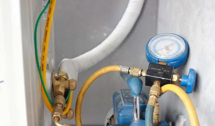 Kỹ thuật viên nối máy hút chân không vào dàn nóng để xử lý trong quy trình lắp máy điều hòa