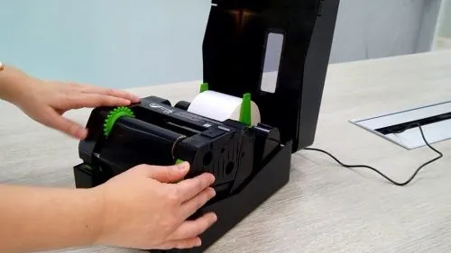 Người dùng thực hiện thao tác mở nắp máy in mã vạch, chuẩn bị cho việc lắp đặt giấy decal theo hướng dẫn cách lắp giấy vào máy in mã vạch