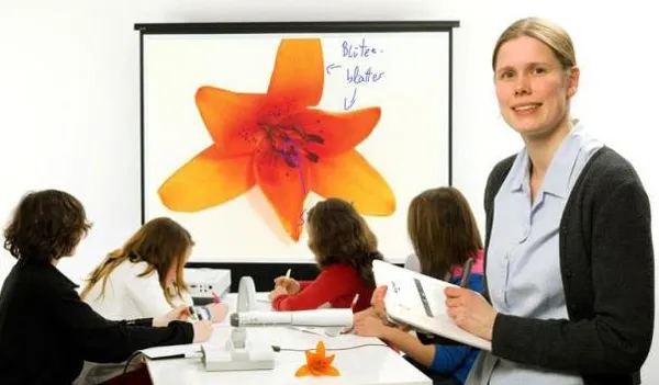 Hình ảnh một người đang điều chỉnh máy chiếu vật thể trên bàn