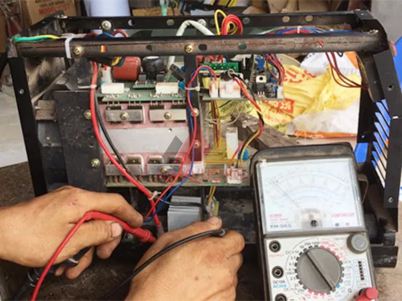 Kỹ thuật viên đang kiểm tra máy hàn điện tử bị mất nguồn bằng đồng hồ vạn năng