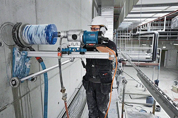 Kỹ thuật viên sử dụng máy khoan bê tông rút lõi với đầy đủ trang bị bảo hộ, tuân thủ các nguyên tắc an toàn lao động trong môi trường xây dựng