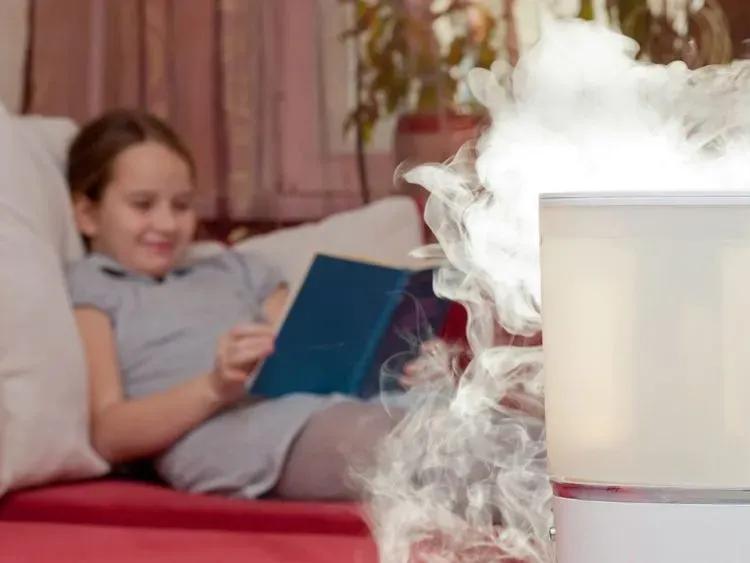 Em bé trong phòng có máy tạo độ ẩm, thể hiện lợi ích cho sức khỏe hô hấp.