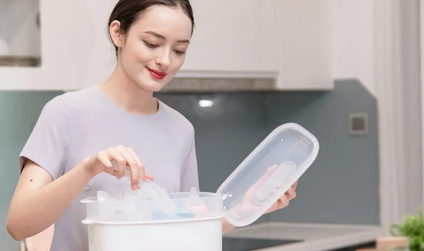 Dùng kẹp gắp chuyên dụng để lấy bình sữa ra khỏi máy tiệt trùng bình sữa Avent khi còn nóng.