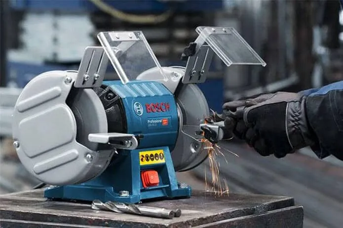 Mũi khoan sắt tiếp xúc nhẹ nhàng với đá mài, giữ đúng góc nghiêng.