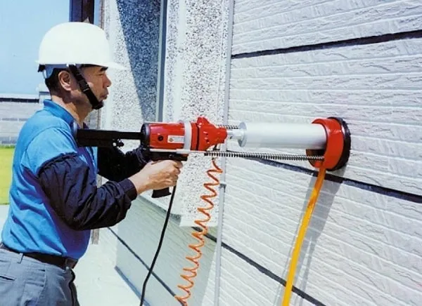 Kỹ thuật viên đang cố định chân đế máy khoan bê tông rút lõi vào bề mặt sàn, đảm bảo độ vững chắc tuyệt đối trước khi tiến hành khoan