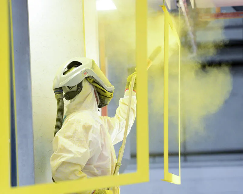 Người thợ đang đeo khẩu trang và kính bảo hộ khi sử dụng máy phun sơn cầm tay