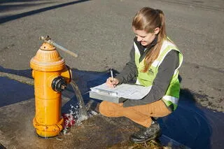 Kỹ thuật viên ghi chép dữ liệu khi kiểm tra áp lực nước tại vòi cứu hỏa, một phần của nghiệm thu quy trình lắp đặt đường ống cấp nước tự chảy.