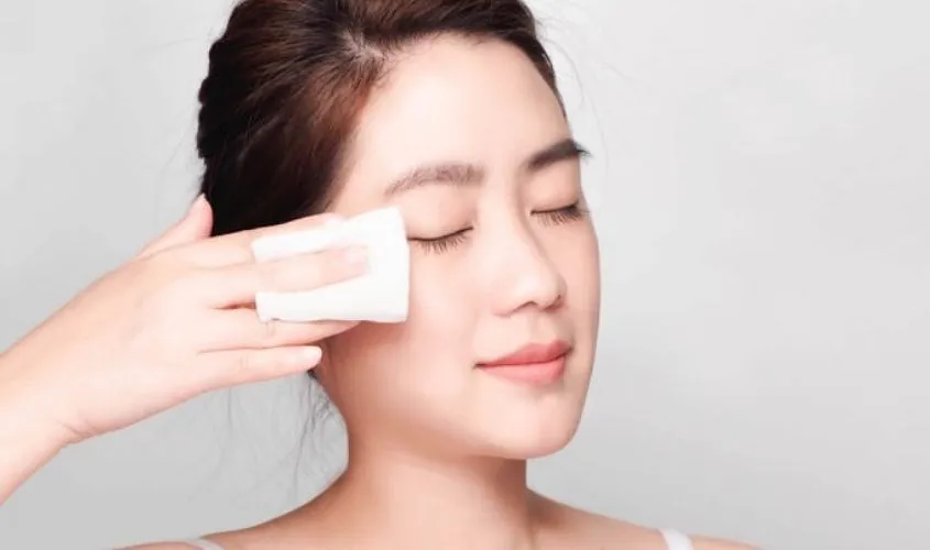 Hình ảnh thể hiện việc sử dụng nước tẩy trang là bước đầu tiên và quan trọng trong cách sử dụng máy rửa mặt Pebble Lisa, giúp loại bỏ bụi bẩn và lớp trang điểm