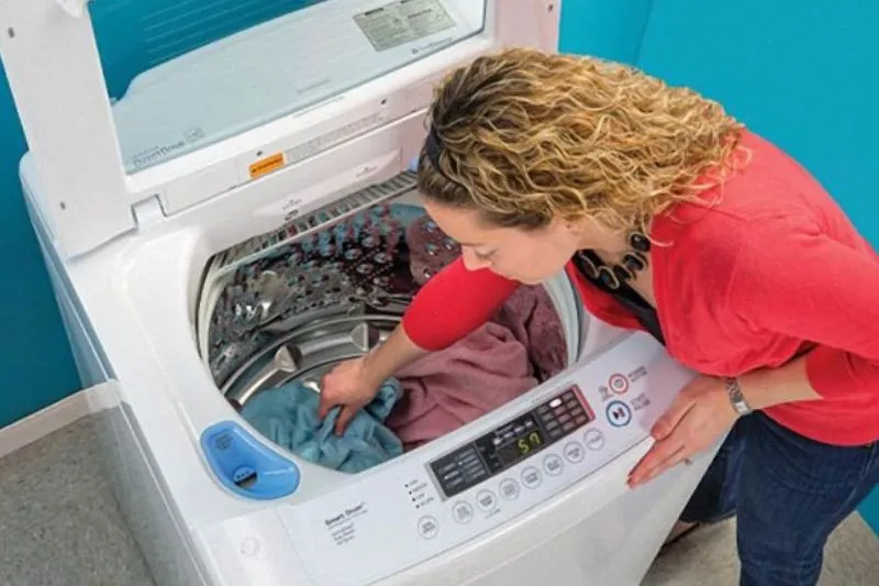 Kỹ thuật viên đang kiểm tra bên trong máy giặt Sanyo