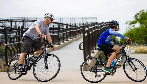 Người đàn ông đang cẩn thận lắp ráp bánh xe vào khung xe đạp màu đen trên sàn nhà xưởng