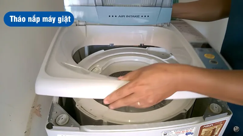 Kỹ thuật viên đang thực hiện cách tháo máy giặt Aqua 8kg, gỡ nắp trên